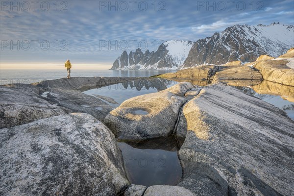 Person with yellow jacket walks along the rocky beach of Tungeneset