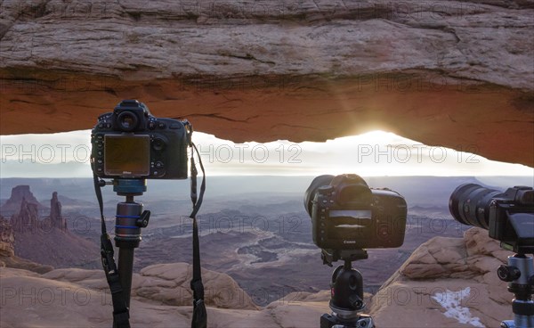 Cameras with view through Mesa Arch at sunrise