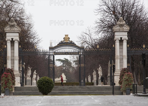 Two runners at the entrance of the Retiro Park on a rainy day in Madrid