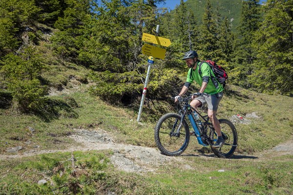Mountain biker rides eMTB on single trail in the mountain forest