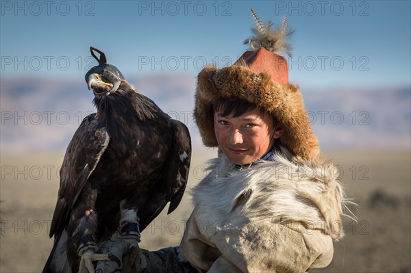 Portrait of young eagle hunter. ÐšÐ°Ð·Ð°ÐºÑƒÑƒÐ´ Ð±Ò¯Ñ€Ð³ÑÐ´Ñ‚ÑÐ¹ Ð±Ð°Ð³Ð° Ð½Ð°ÑÐ½Ð°Ð°ÑÐ°Ð° ÑÑ…Ð»ÑÐ½ Ð½Ó©Ñ…Ó©Ñ€Ð»Ó©Ð¶ ÑÑ…ÑÐ»Ð´ÑÐ³. Bayan-Ulgii province