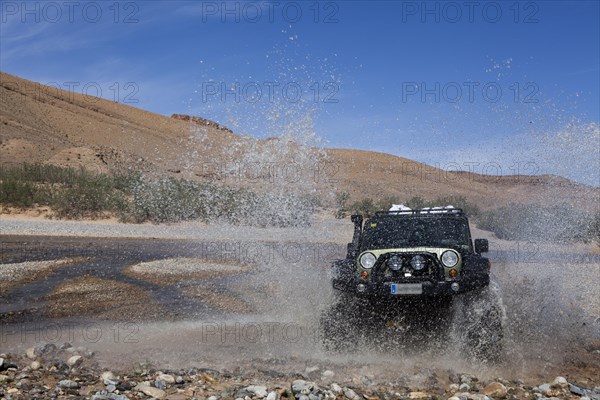 Off-road vehicle crosses a river in the Middle Atlas