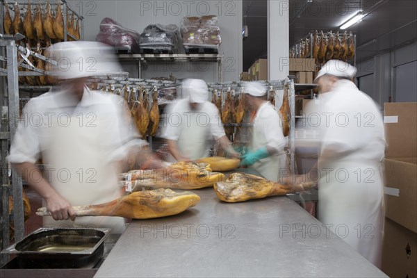 Employees select pieces from Jamon Serrano for packaging