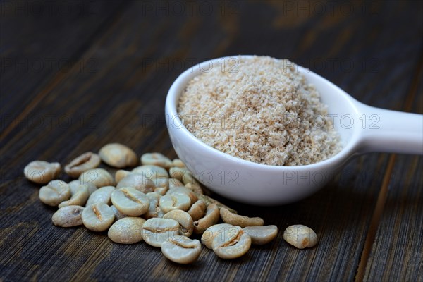 Green coffee beans and unroasted coffee powder in spoon