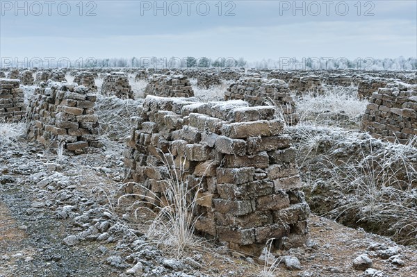 Piled up peat sods in the bog in winter at hoarfrost