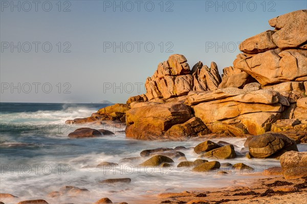 Red granite rocks and rough sea