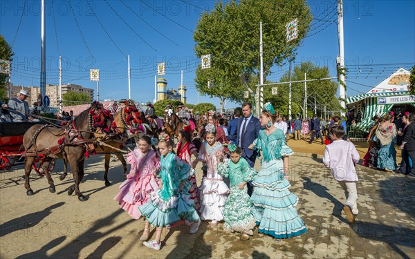 Spanish family with colourful flamenco dresses in front of marquees