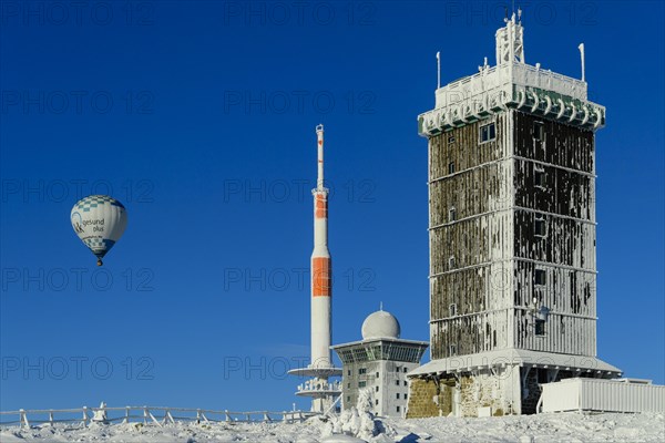 Hot-air balloon with transmitter mast and Brocken hostel on the winter snow-covered Brocken