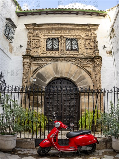 Red scooter Piaggio Vespa in front of an entrance door