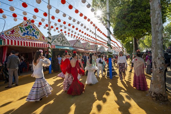 Spanish women with colorful flamenco dresses in front of marquees