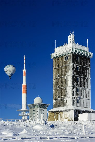 Hot-air balloon with transmitter mast and Brocken hostel on the winter snow-covered Brocken