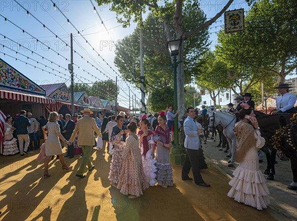 Spanish women with colorful flamenco dresses in front of marquees