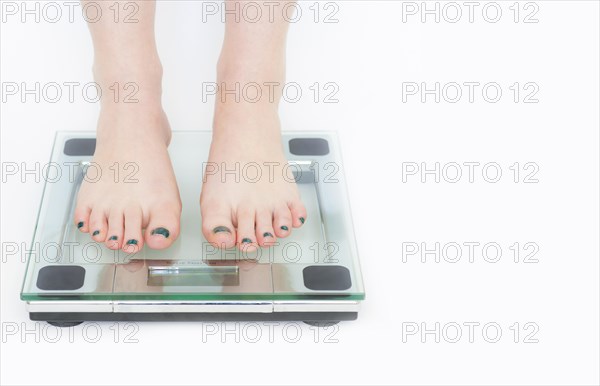 Woman in a weighing machine with white background