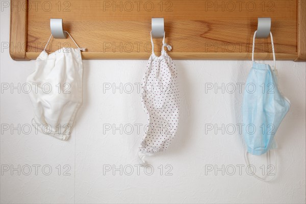 Various corona protection masks hang on coat hooks