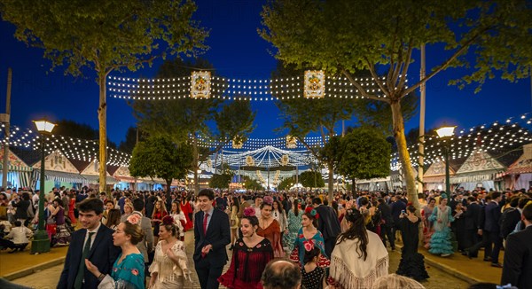 Spaniards celebrating in traditional clothes in front of lit marquees