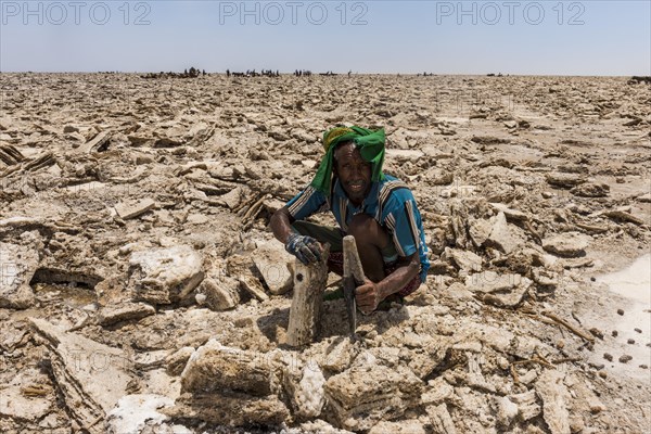 Afar nomad with knife cutting out salt plates