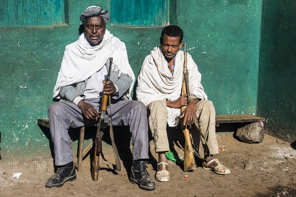 Two sentries with rifles sitting on a bench