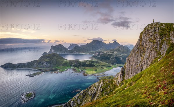 Tiny person stands at the summit and looks out over the wide sea