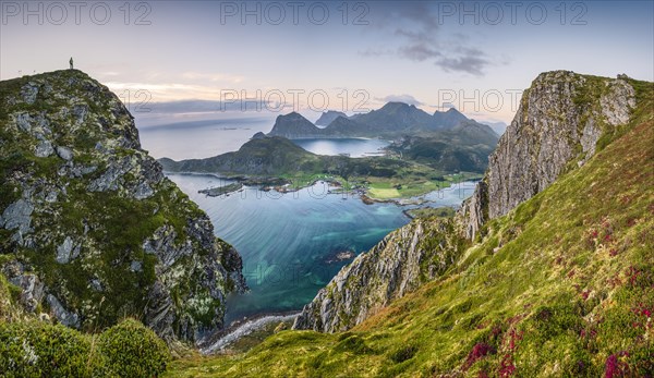 Tiny person stands at the summit and looks out over the wide sea