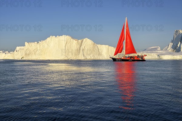 Red sailing boat in front of icebergs