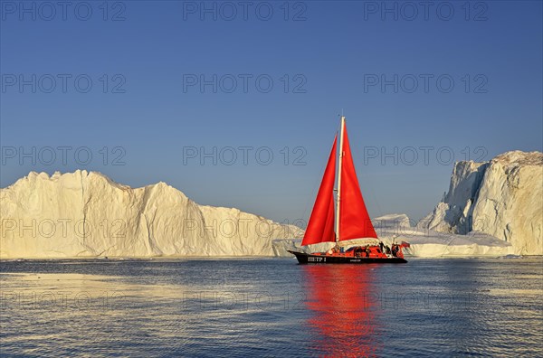 Red sailing boat in front of icebergs
