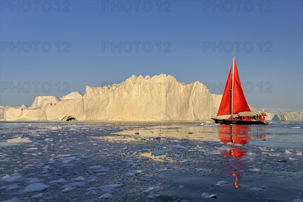 Red sailing boat in front of icebergs