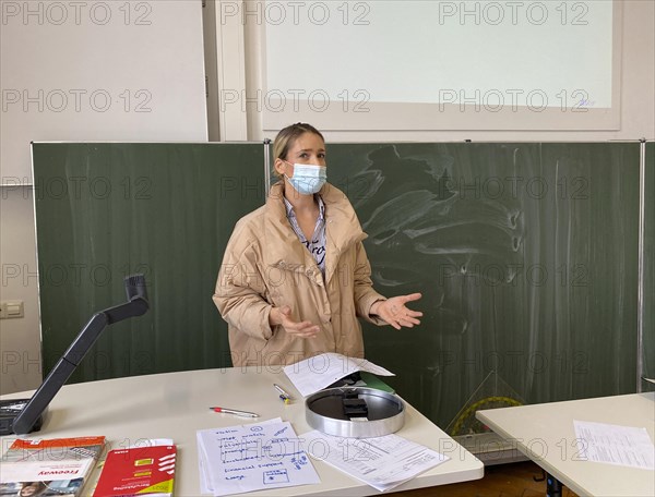 Teacher with thick winter jacket and face mask in classroom teaching