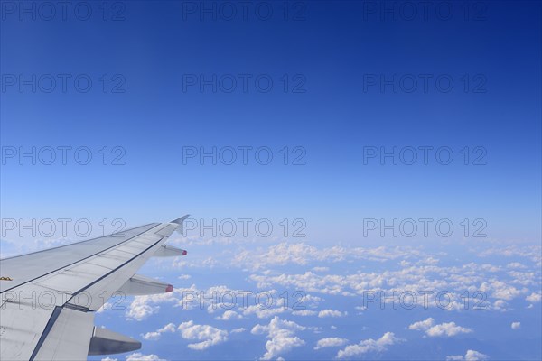 Airplane wing over a bright blue sky