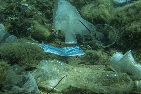 Discarded used medical face mask along with other plastic debris lies on the seabed. Plastic and other garbage polluting in the Adriatic Sea. Becici