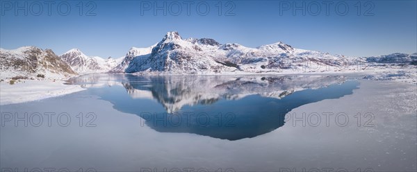 Deep wintry mountain range reflected in the blue sea