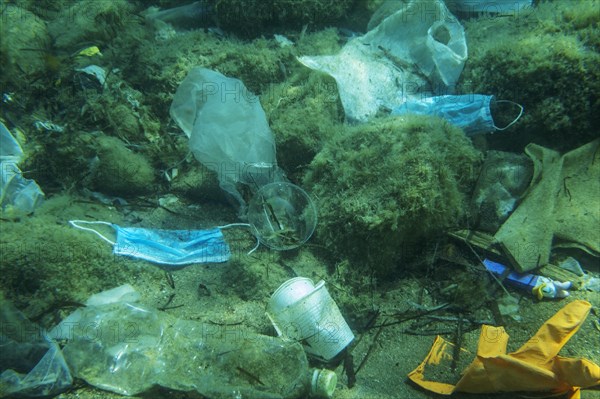 Discarded used medical face mask along with other plastic debris lies on the seabed. Plastic and other garbage polluting in the Adriatic Sea. Becici
