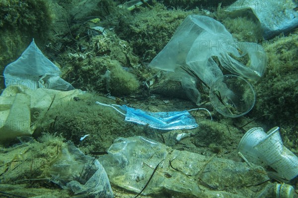 Discarded used medical face mask along with other plastic debris lies on the seabed. Plastic and other garbage polluting in the Adriatic Sea. Becici