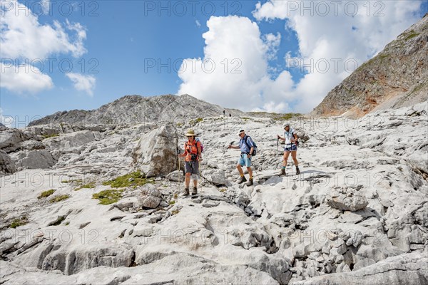 Three hikers in a landscape of washed-out karst rocks