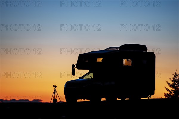 Silo hut motorhome and photo tripod with camera bag and camera at dusk