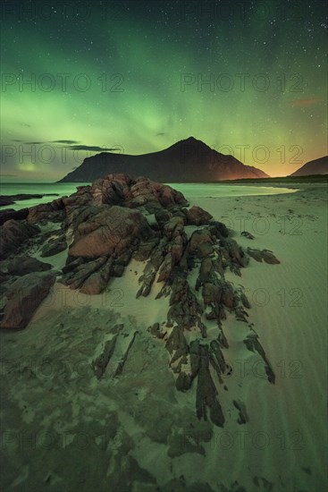 Northern lights over rocky sand beach