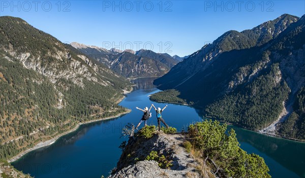 Two hikers stretch arms in the air