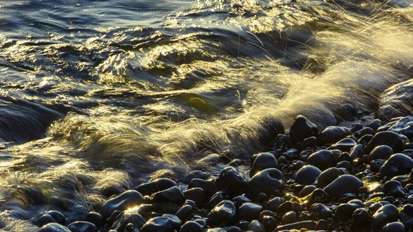 Waves and spray on the beach at sunrise