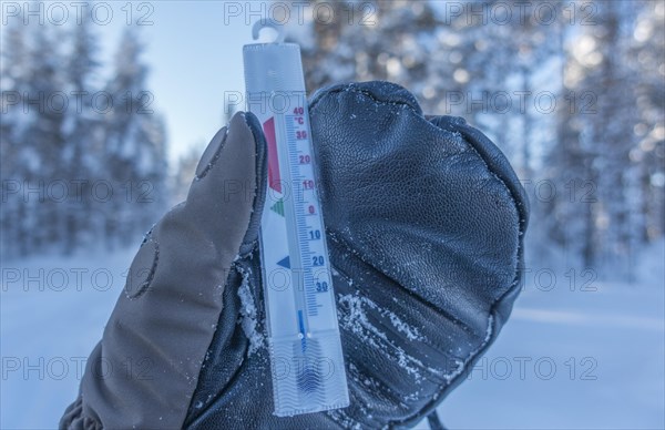 Hand with thick mitten holds thermometer at minus 36 Celsius