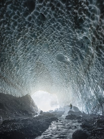 Mountaineer in the ice chapel with meltwater stream