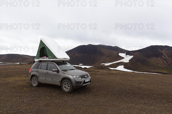 Off-road vehicle with roof tent on barren plateau