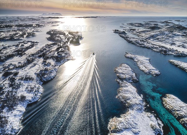 Motorboat sailing through a winter fjord landscape with small islands