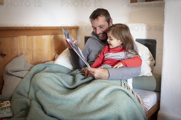 Father reading aloud with daughter