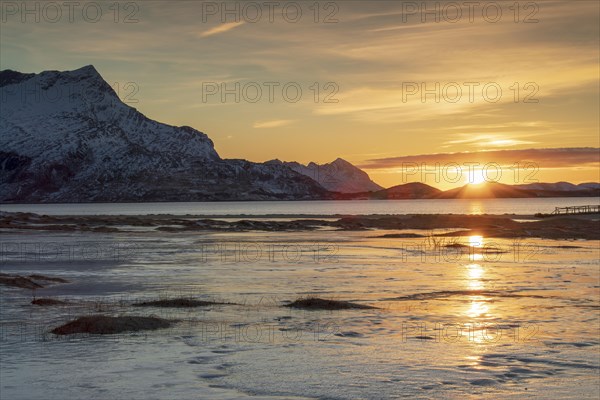 Sunset at sandy beach covered with ice