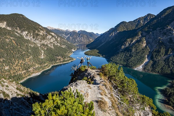 Two hikers stretch arms in the air