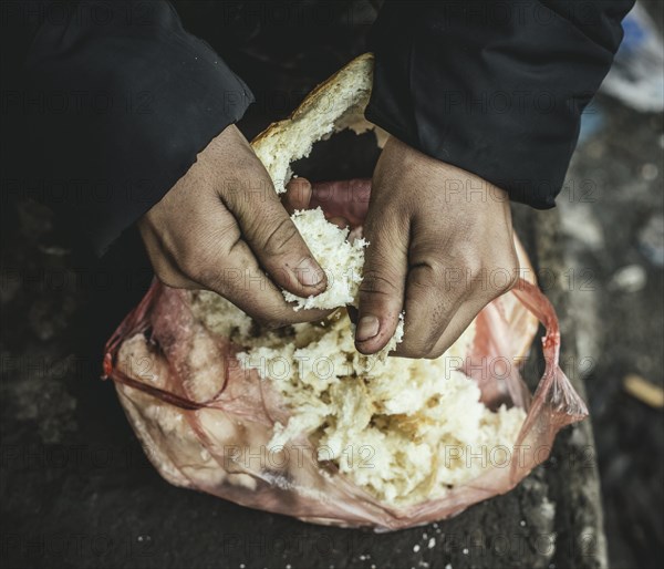 Escaped man plucks stale bread for a meal