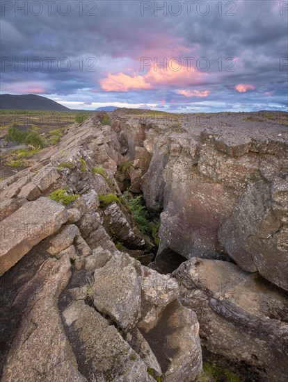 Red column in the plain with dramatic clouds in the evening sky in the fault zone