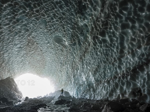 Mountaineer in the ice chapel with meltwater stream