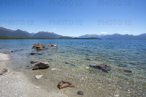 Young man jumps from stone into water