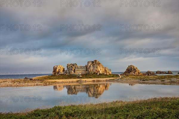 House between granite rocks with water reflection