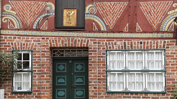 Historical half-timbered house with crooked beams and modern inscription to protect against demolition